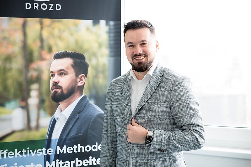 Ioan Drozd steht mit einem Kollegen vor dem DROZD Banner im Büro in St. Pölten